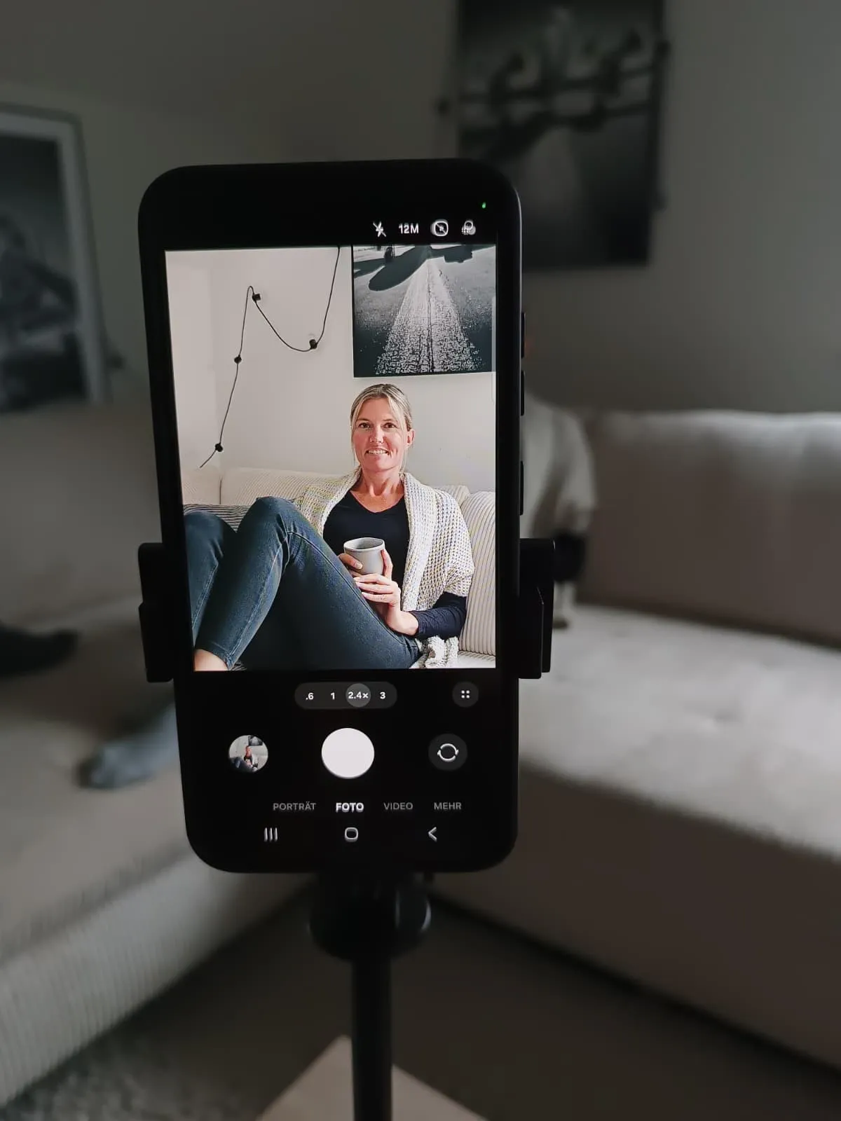 Christine wird auf dem Sofa mit einem Smartphone auf einem Stativ gefilmt