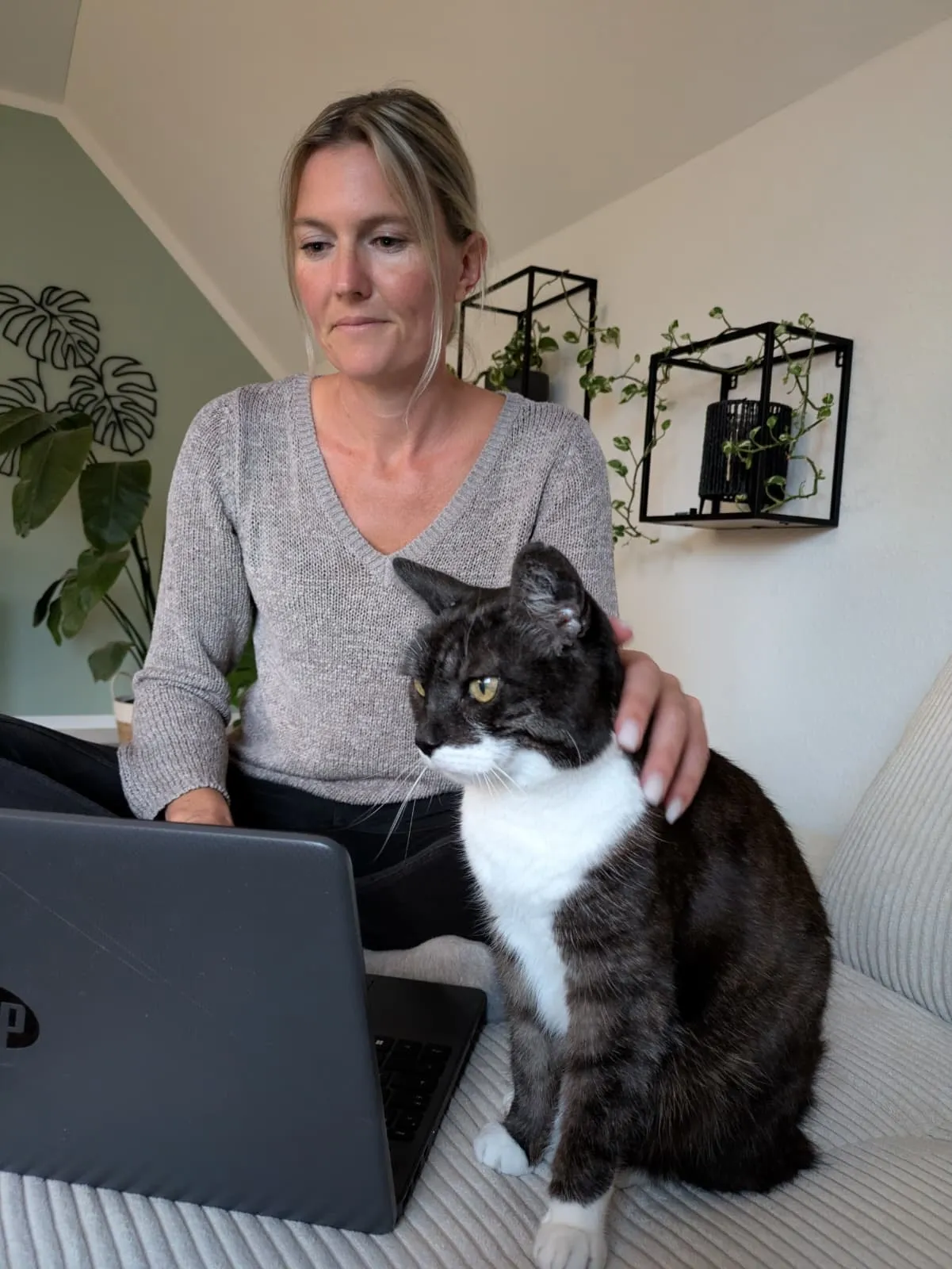 Christine arbeitet am Laptop, neben ihr sitzt ihre Katze